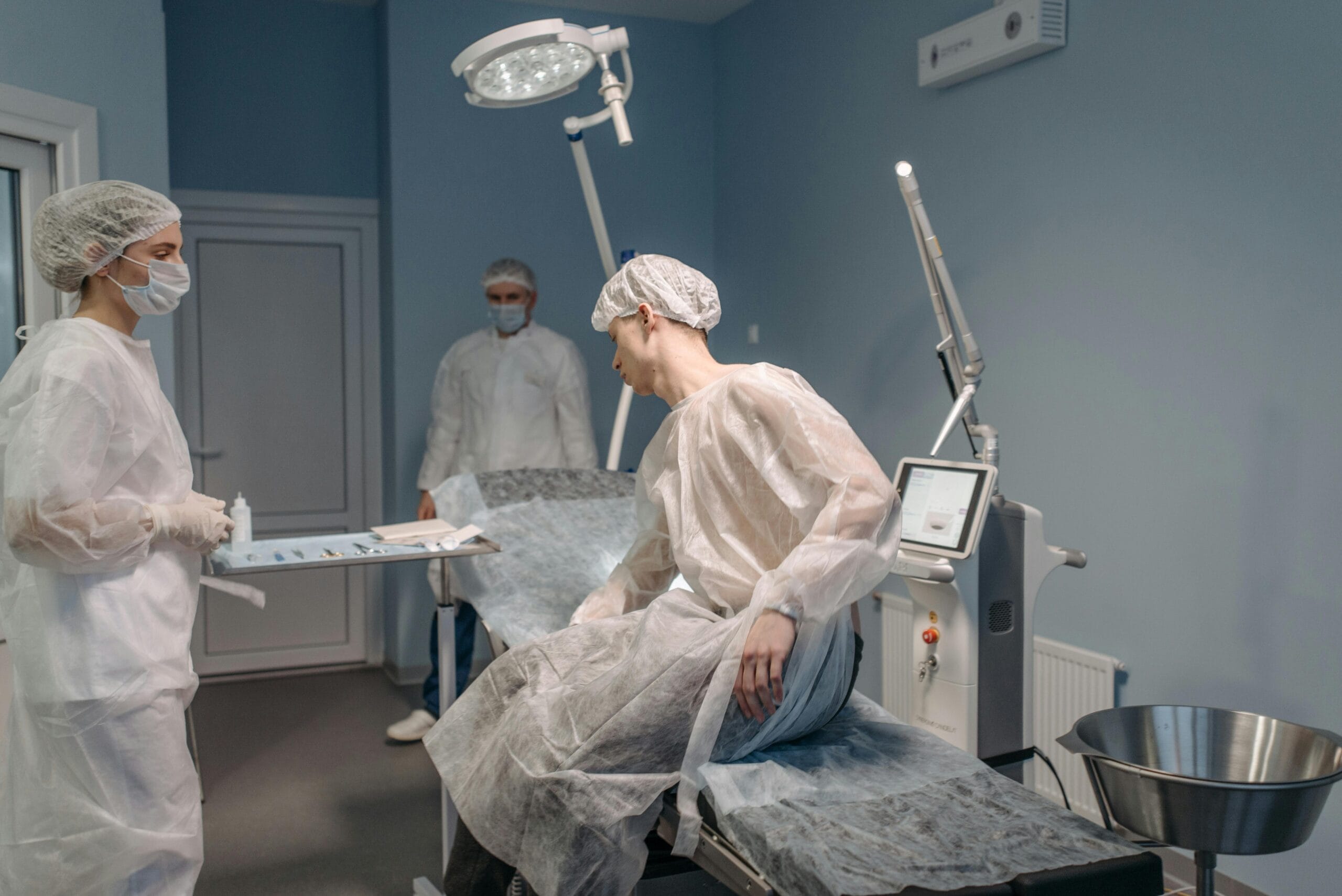 pexels-photo-7108222-7108222 A medical team in sterile gowns prepares for a clinical procedure in a well-equipped room.